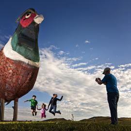 Family jumping in front of the metal pheasnt sculptures