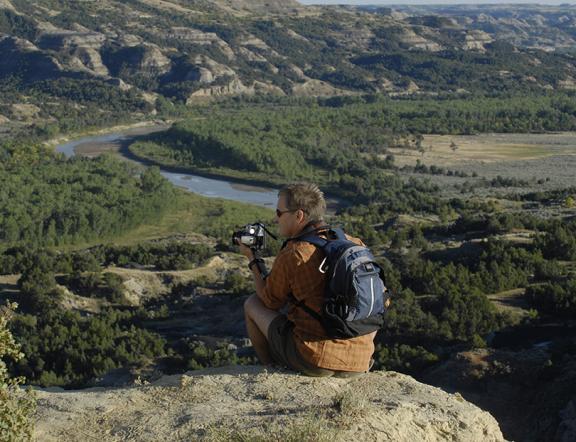 A man is taking a picture of a scenic view at Theodore Roosevelt National Park