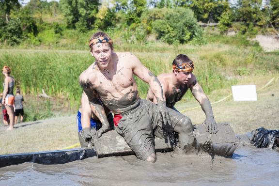 Group of individuals crawling through mud as part of a race