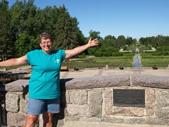 Connie Lagerquist standing with arms outstretched in the International Peace Garden