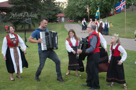 A man playing an accordion with people in traditional attire