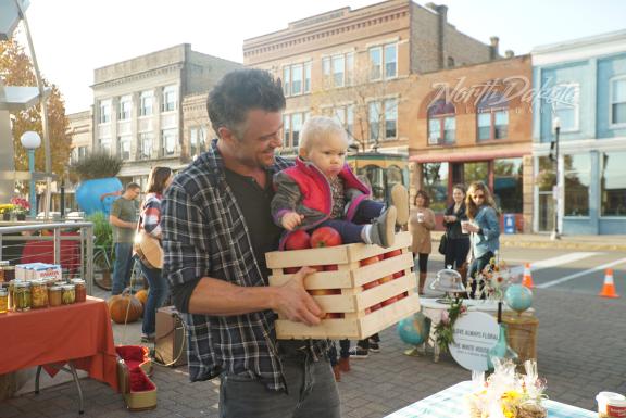 A man holding a baby in a wooden crate at an outdoor market