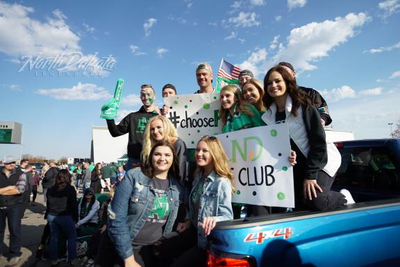 A group of people posing with a sign at an outdoor event