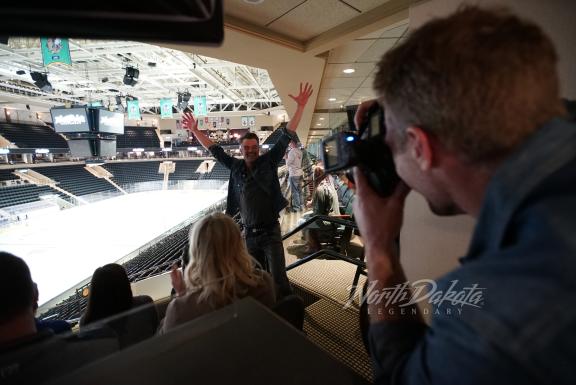 A man being photographed while raising his arms in excitement