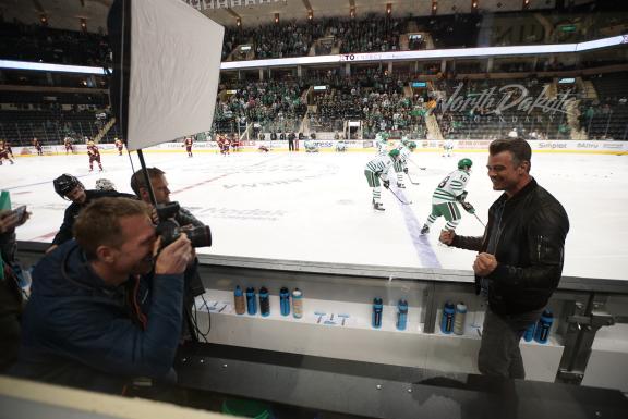 A man and a photographer at a hockey game