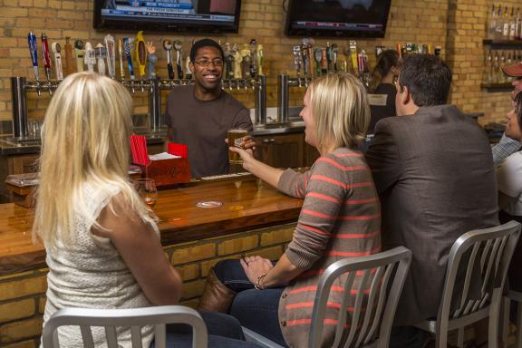 A bartender serves drinks to patrons at a lively bar