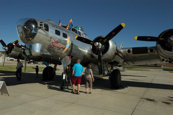 A large, vintage military aircraft with propellers is displayed outdoors