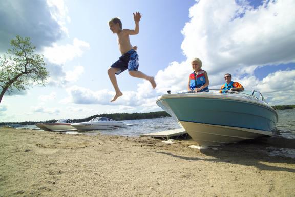 A person jumps off a boat into the water, while another person watches from the boat