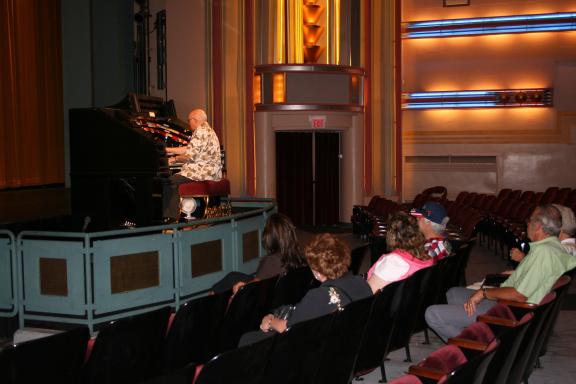 The interior of a theater with people seated and watching a performance or presentation