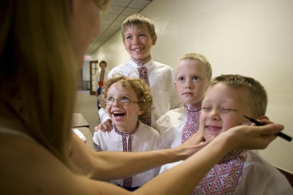 A woman is applying makeup to children