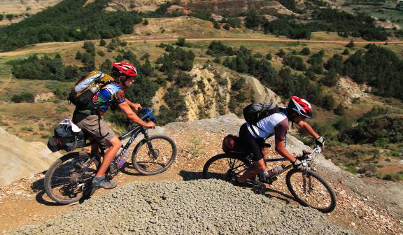 Two people mountain biking in over a valley.
