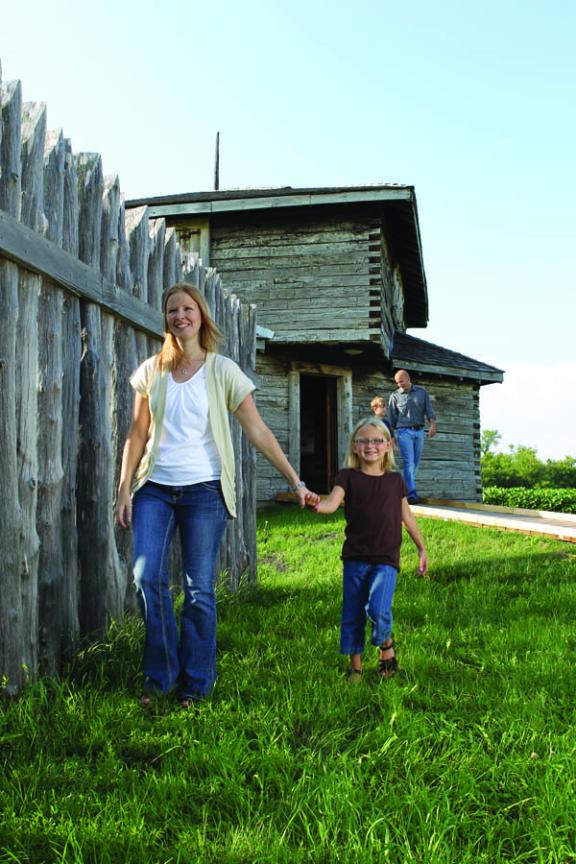 A family is walking around the grounds of Fort Abercrombie