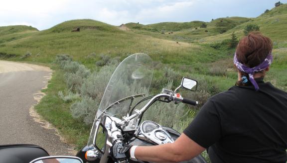 Man looks out at the hills of North Dakota while riding on a motorcycle