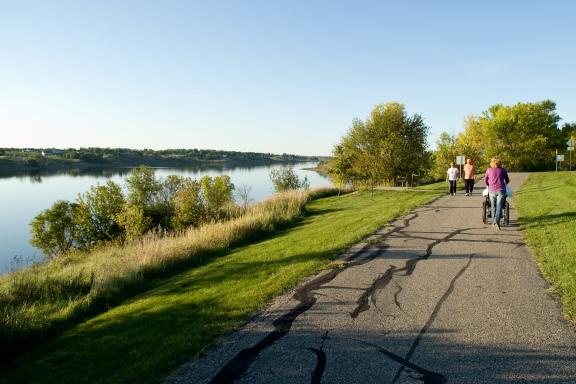 A path runs along a reservoir, with people walking and enjoying the view