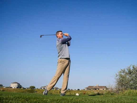 Mike Herzog is swinging a golf club on a golf course