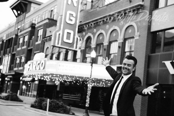 A man in a suit with arms open in a city street