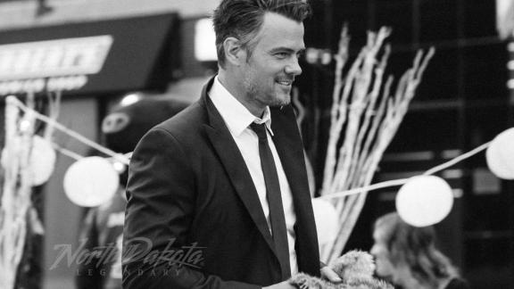 Man in a suit smiling at an outdoor event