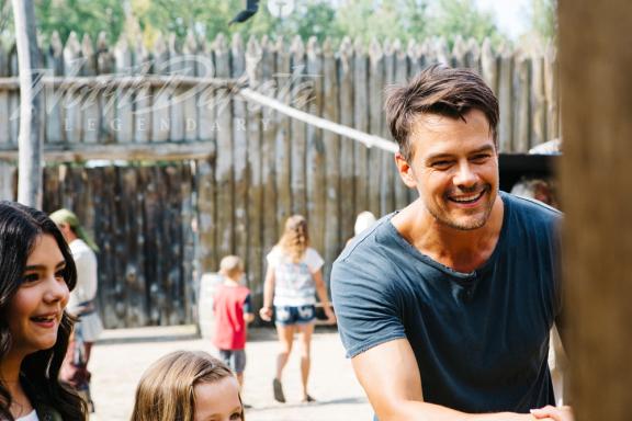 A man and a woman smiling outdoors with people in the background