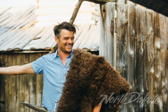 A man smiling next to a bear pelt