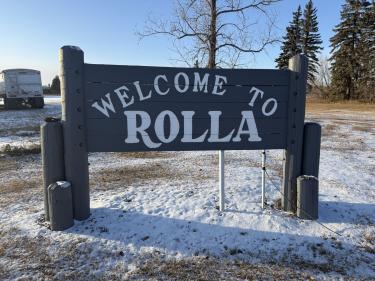 welcome to rolla sign in snowy northern landscape with evergreen trees and frozen lake, winter destination entry photo