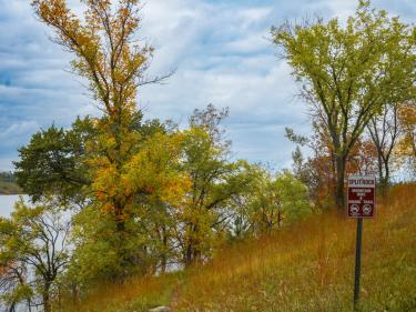 scenic autumn landscape at split rock mountain park with golden trees, blue sky, lake views, and hiking trail sign among rolling hillside vegetation. photo