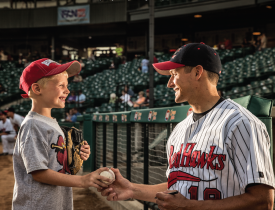 red hawks team member giving ball to a child